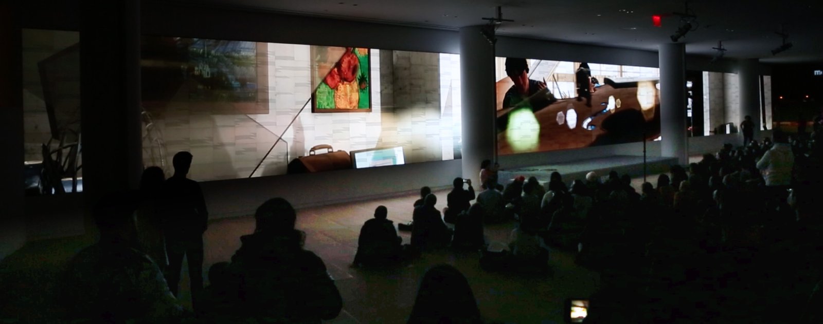 Estranged Stars playing across the full panoramic wall, two scenes side by side above a seated audience