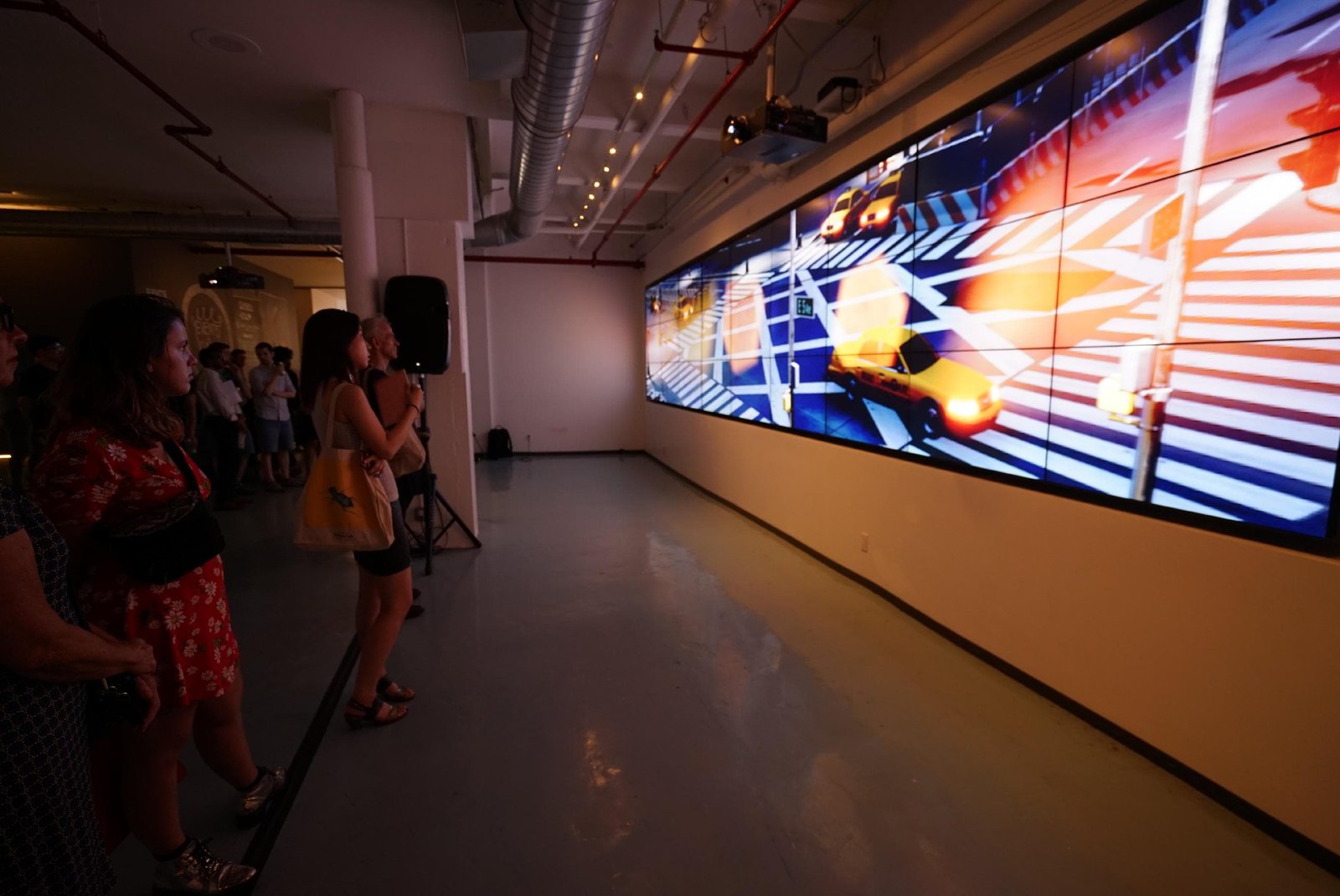 Estranged Stars projected across a panoramic wall of screens, audience silhouetted in front of the neon-crossroads scene