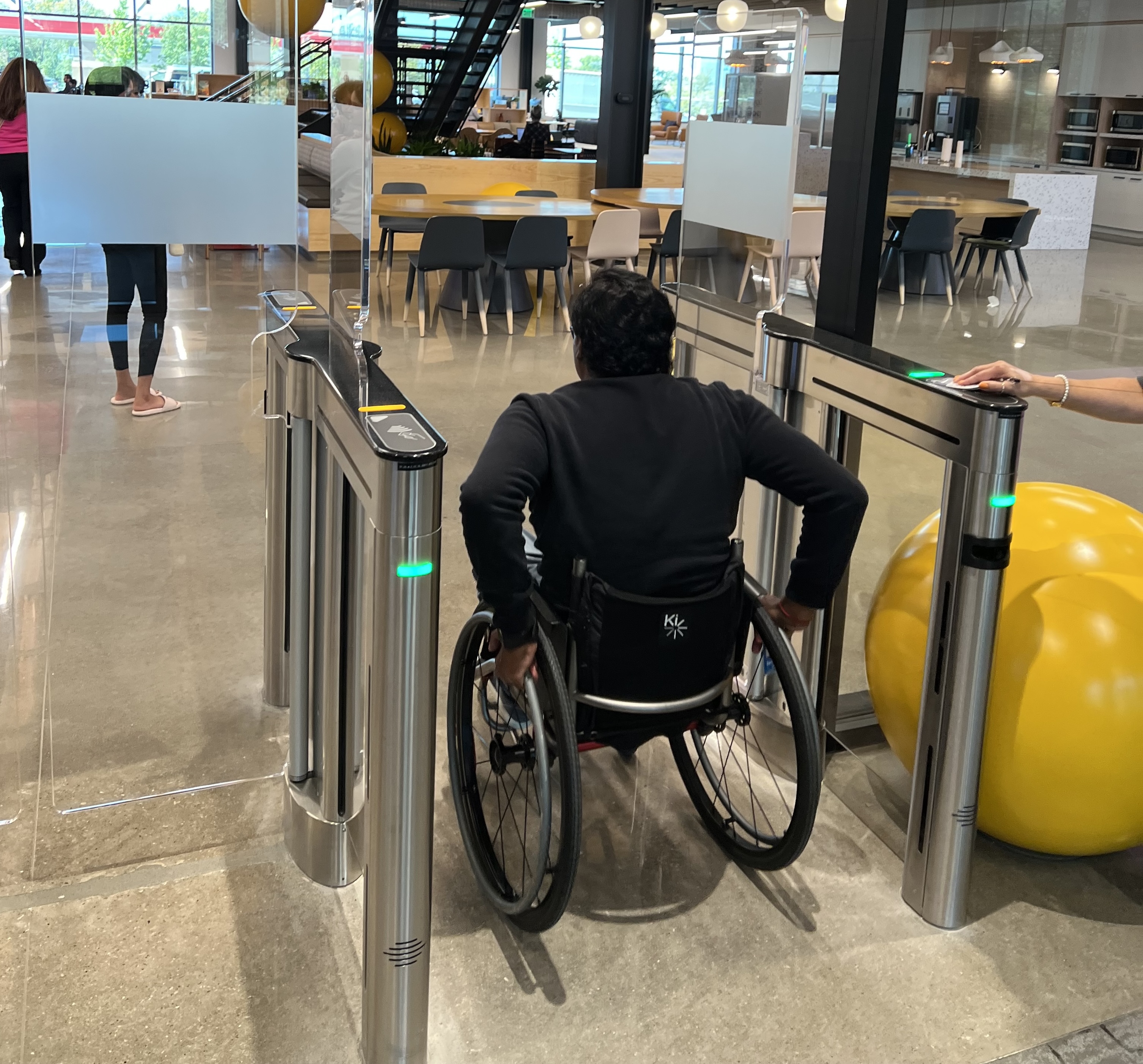 Visitor using a wheelchair scanning their badge at a campus turnstile
