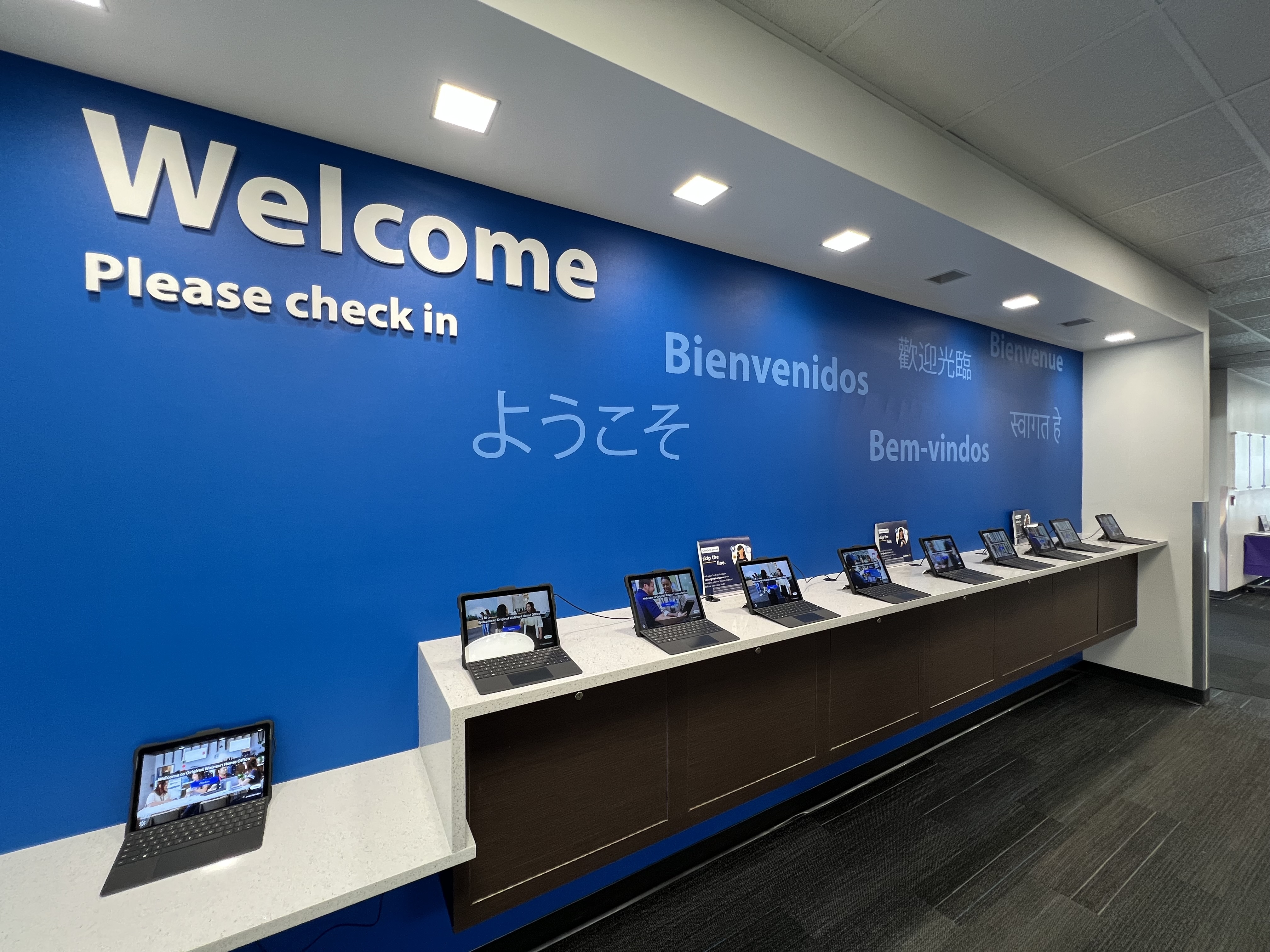 Deployed check-in kiosks at Walmart campus lobby with multilingual Welcome wall